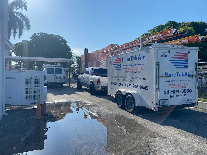 Pure Tek Air enclosed utility trailer loaded with ladders beside a portable cooler